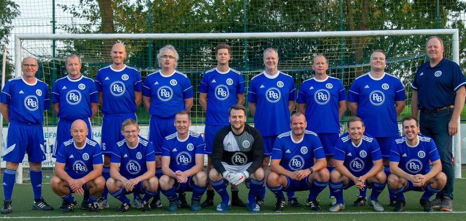 Mannschaftsfoto einer Fußballmannschaft in blauen Trikots vor einem Tor auf einem Rasenplatz.