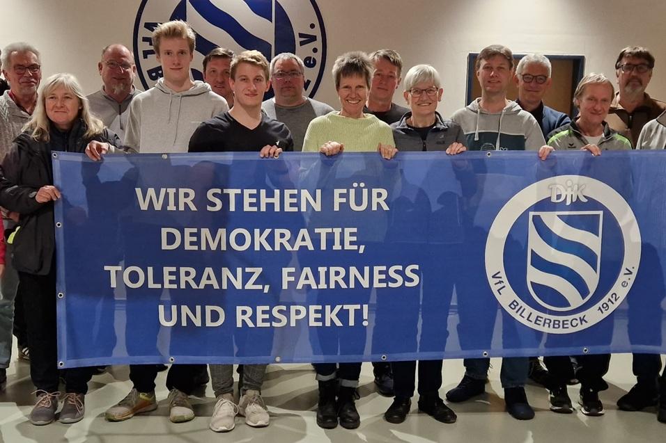 Gruppe von Menschen h&auml;lt ein Banner mit der Aufschrift: &bdquo;WIR STEHEN F&Uuml;R DEMOKRATIE, TOLERANZ, FAIRNESS UND RESPEKT!&ldquo;