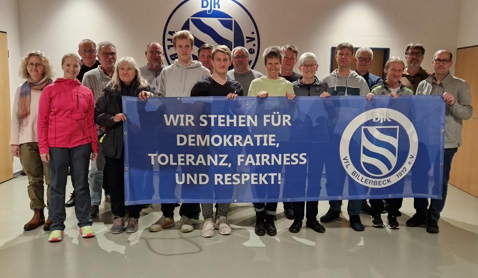 Gruppe von Menschen h&auml;lt ein Banner mit der Aufschrift: &bdquo;WIR STEHEN F&Uuml;R DEMOKRATIE, TOLERANZ, FAIRNESS UND RESPEKT!&ldquo;