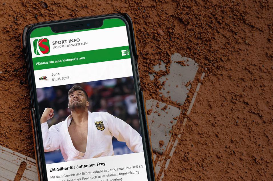 Smartphone auf rotem Sportplatz mit einer Judo-Nachricht und einem Athleten in einem wei&szlig;en Gi auf dem Bildschirm.