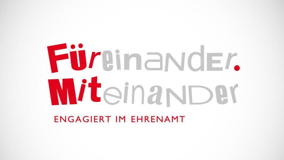Text mit den Worten „Für einander. Miteinander. Engagiert im Ehrenamt“ auf hellem Hintergrund.